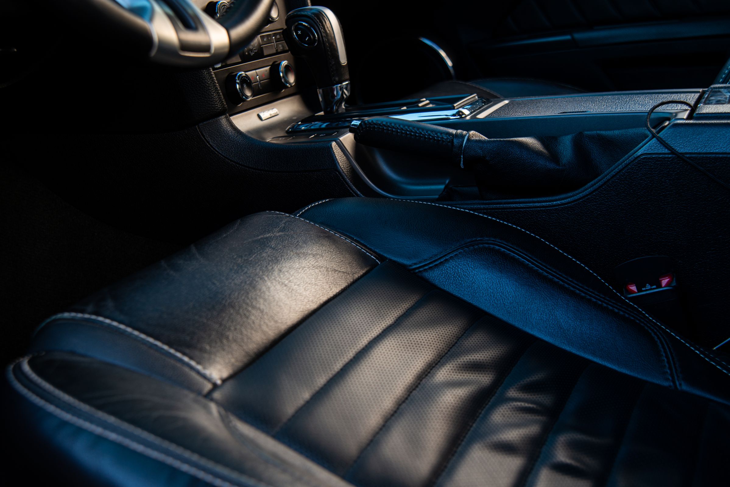 Black leather car seats and center console that need conditioning to prevent summer heat cracking