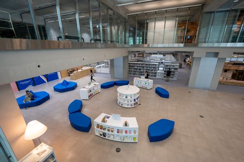 Free Spacious modern library interior with blue seating, bookshelves, and open design. Stock Photo