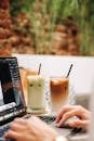 Hands Typing on Laptop with Cocktails with Straws near