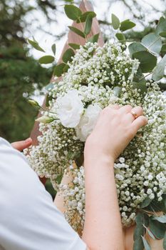 Close-up of hands arranging fresh white flowers outdoors, capturing nature's beauty.