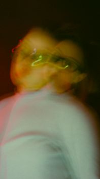Blurred artistic portrait of a woman with neon light effects, creating a dynamic and surreal visual.