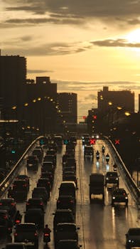 Silhouetted skyline and traffic on a rainy expressway at sunset in Nonthaburi, Thailand.