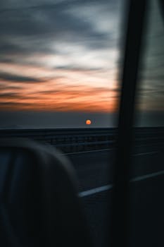 Scenic sunset seen from a car window driving down a highway, creating a serene evening travel ambiance.