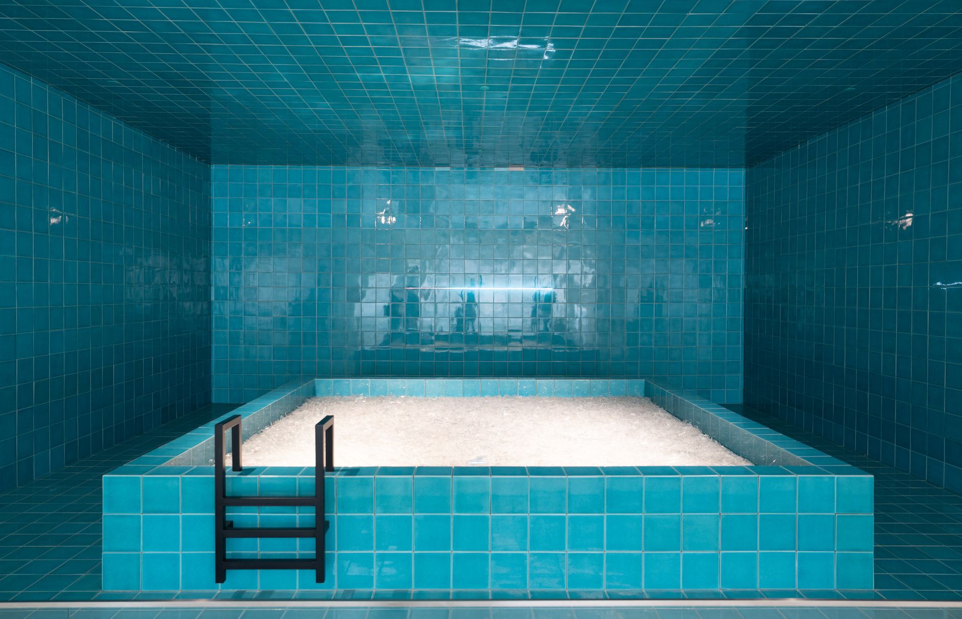 A tiled indoor magnesium pool lit in deep blue, echoing the mood-first design of a coastal spa ritual.