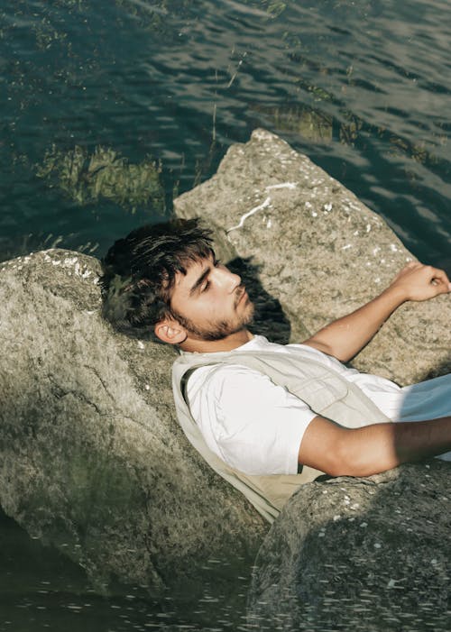 Young Man Relaxing on Lakeshore Boulders