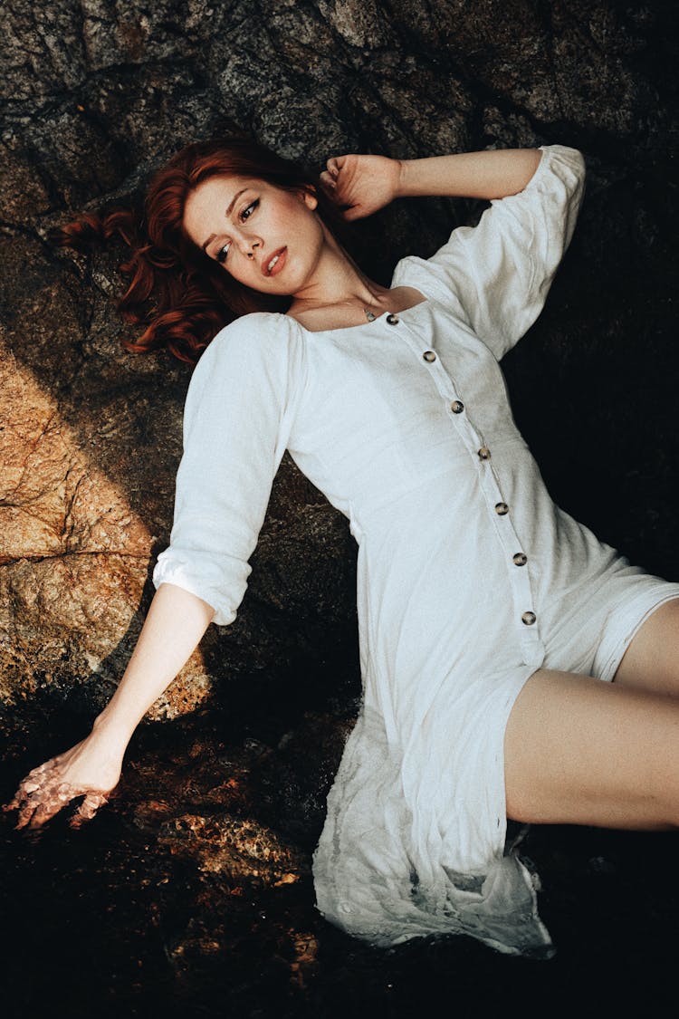 Portrait Of A Pretty Redhead Leaning On A Coastal Rock Wall