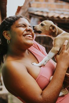 A woman smiling and holding a playful puppy outdoors, showcasing a joyful connection.