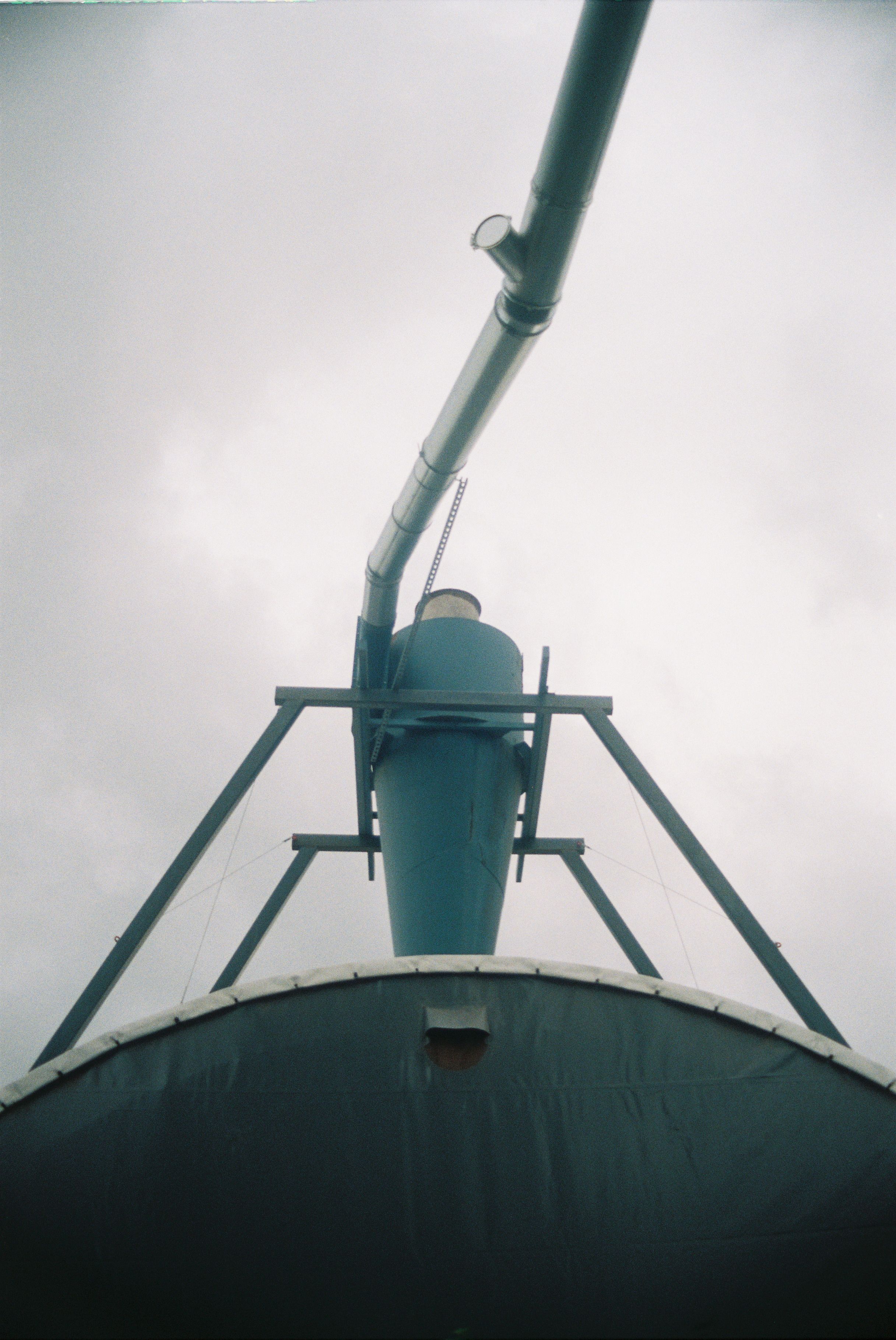 A low angle view of an industrial metal pipe structure against a cloudy sky.