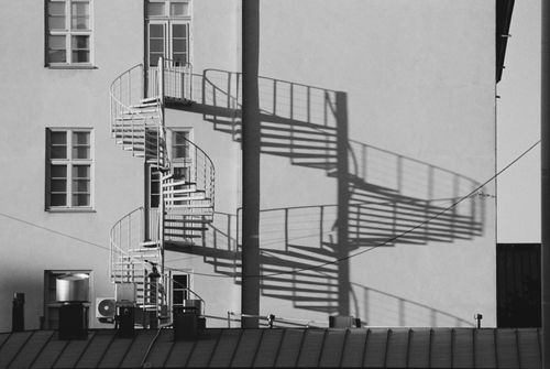 Free Monochrome image of spiral staircase casting shadows on urban building wall. Stock Photo