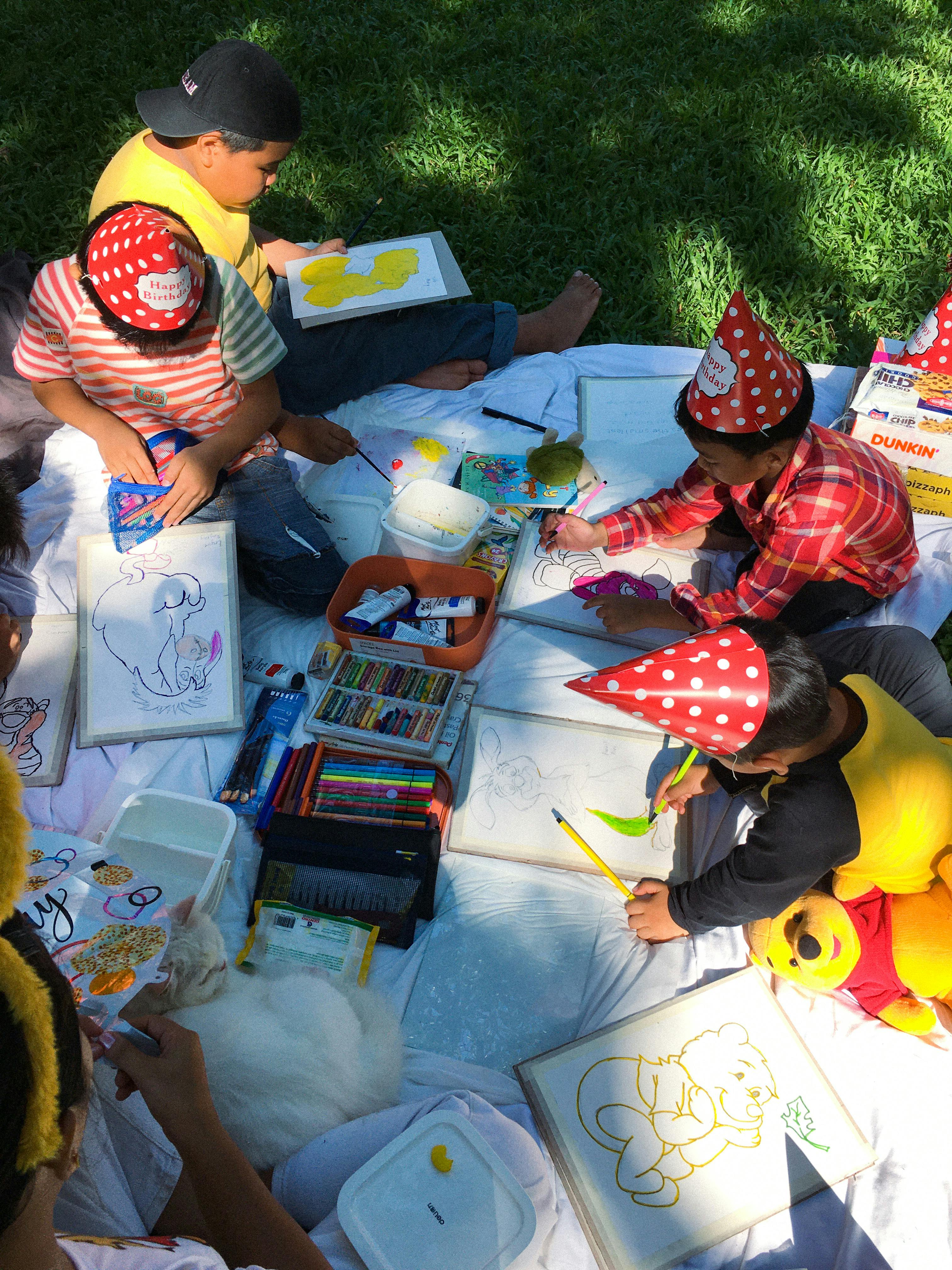 children sitting on a blanket with birthday hats