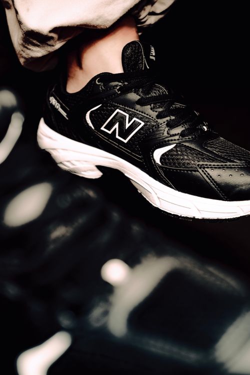 Free Modern black athletic shoe with white sole on a dark background, showcasing sporty elegance. Stock Photo
