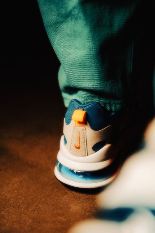 Free Focus on a modern sneaker with blue, white, and orange details on a casual background. Stock Photo