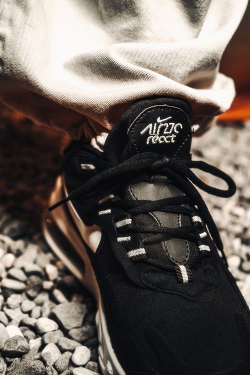 Free Detailed image showcasing a sleek black sneaker on gravel, highlighting fashion-forward footwear. Stock Photo