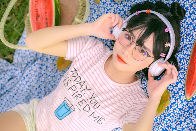 Girl In Wireless Headphones Lying On A Picnic Blanket