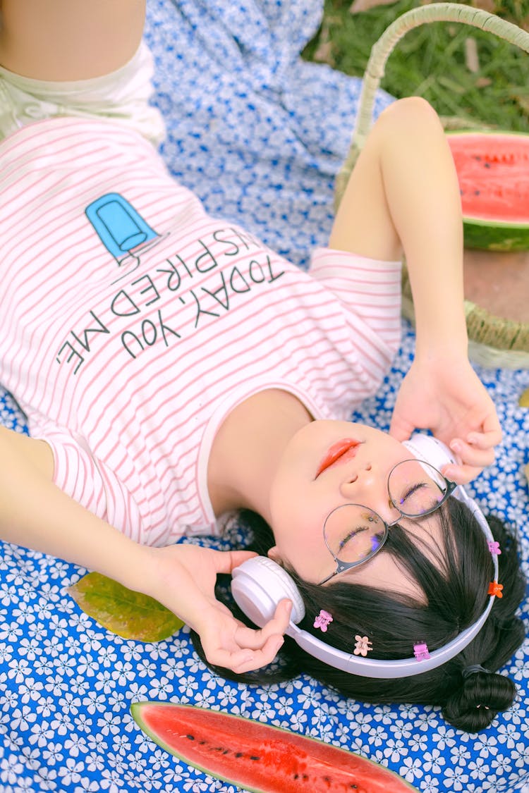 Girl Listening To Music Lying On A Picnic Blanket