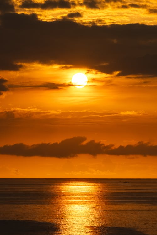 Clouds and Sunlight on Yellow Sky over Sea at Sunset