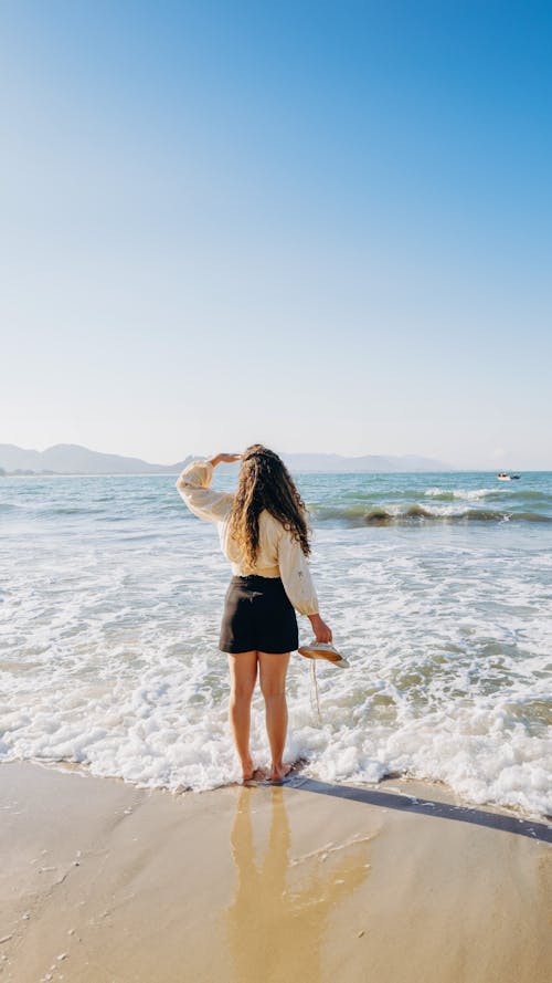 Tourist Soaking Feet in the Sea Looking Towards the Sun