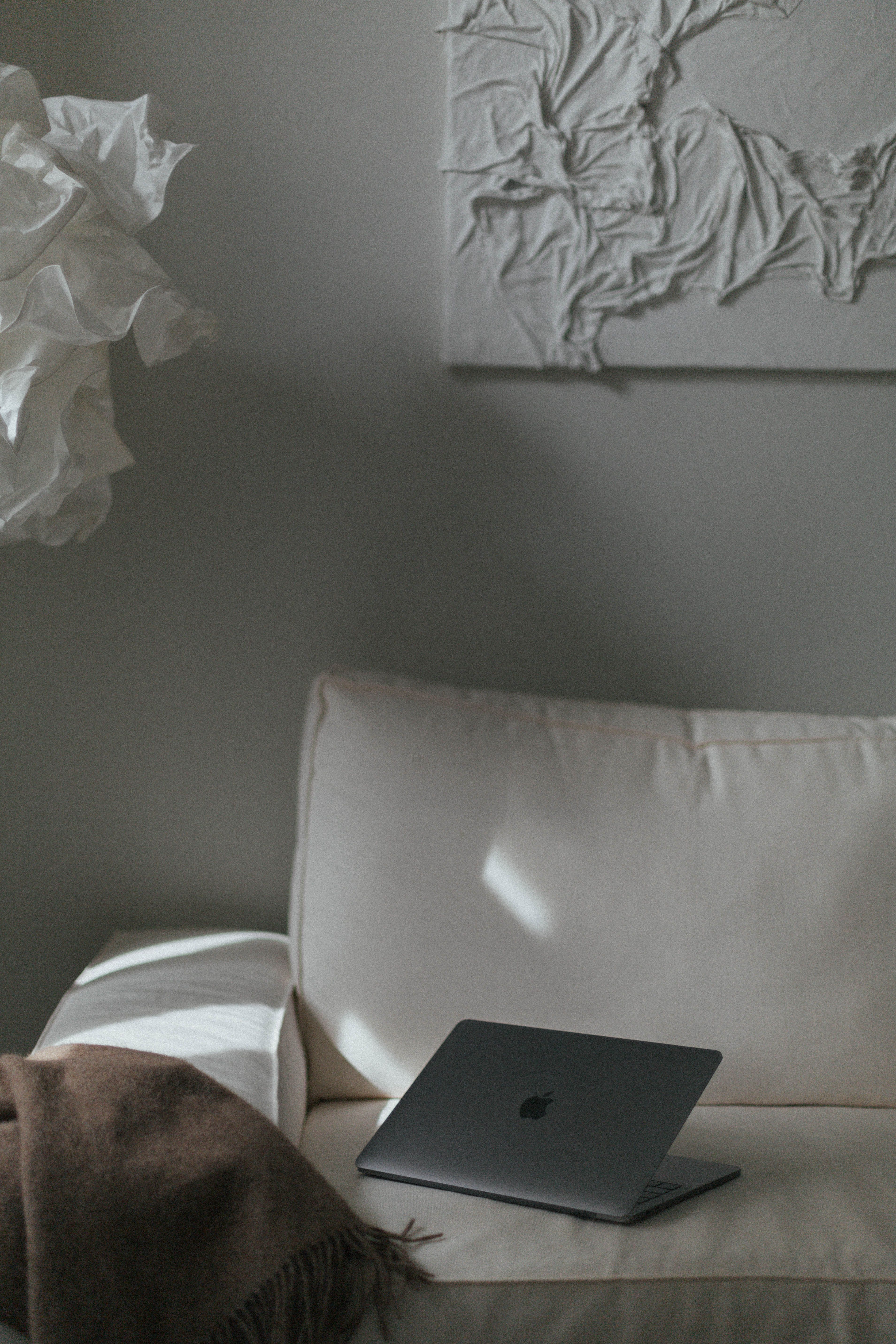 A sleek laptop on a modern white sofa with contemporary art in a cozy living room.