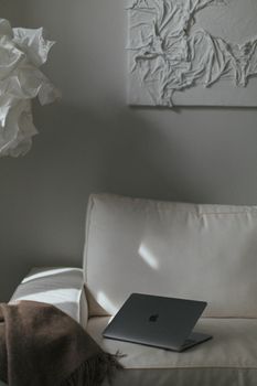 A sleek laptop on a modern white sofa with contemporary art in a cozy living room.