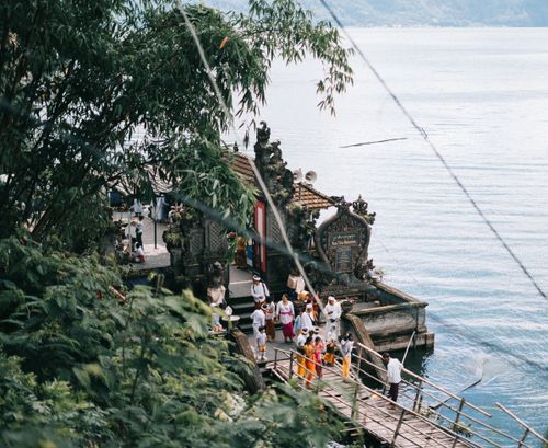 Free Group of people gathering at a traditional shrine by a serene lake in Bali, Indonesia. Stock Photo