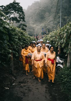 在文化仪式上，一群穿着传统服装的成年人走过森林小路