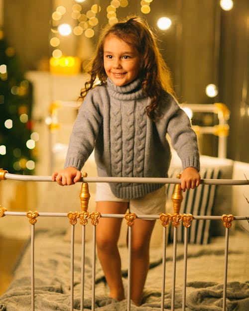 Girl in Turtleneck Woolen Sweater Standing on Bed