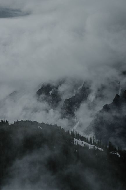 A dark and misty mountain landscape enveloped in thick fog.
