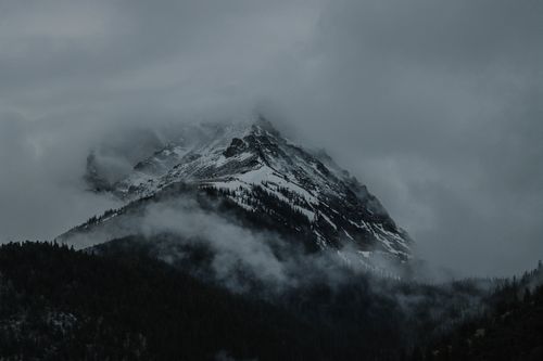 Free Misty fog envelops a snowy mountain peak, creating a dramatic landscape. Stock Photo