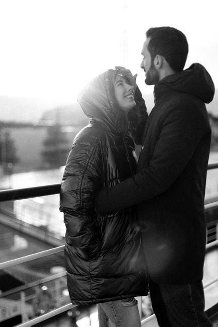 A couple standing on a deck embracing in a loving moment during daytime.