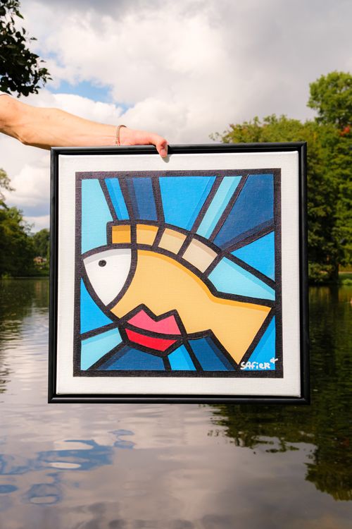 Free A vibrant abstract fish painting held above a lake, blending art and nature. Stock Photo