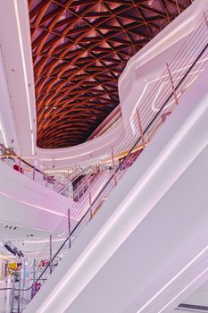 Contemporary shopping mall with intricate geometric ceiling and bright lighting creating a futuristic look.