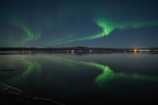 Mesmerizing aurora borealis reflecting over calm waters in Hveragerði, Iceland at night.