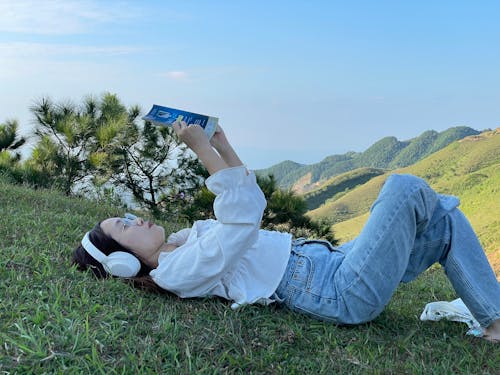 Woman Lying Down on Grass and Reading Book
