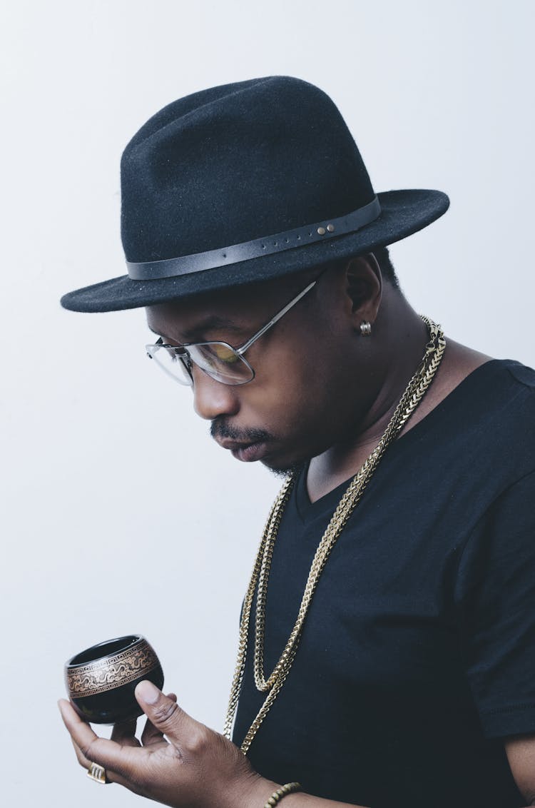 Photo Of Man In Black T-shirt And Fedora Holding An Object