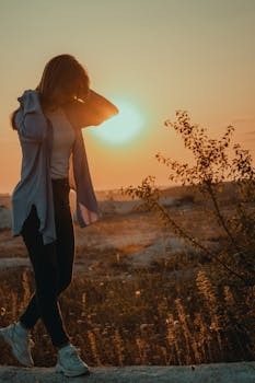 Young woman walking outdoors in warm sunset light, capturing serene and casual elegance.