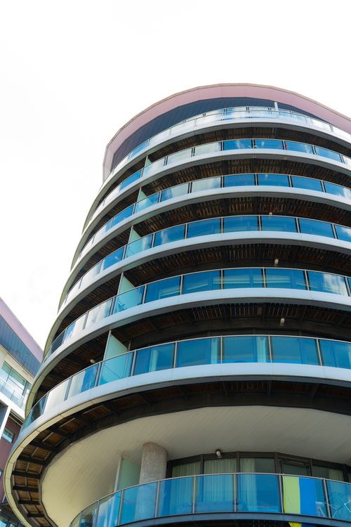 Free Low angle view of a modern building with curved glass balconies under a bright sky. Stock Photo