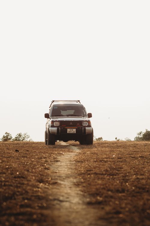Free A Mitsubishi Pajero SUV drives on a rugged dirt road surrounded by nature, capturing adventure and exploration. Stock Photo