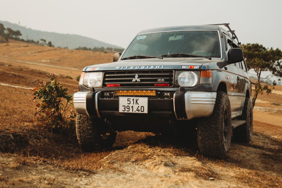 rugged Mitsubishi Pajero SUV driving on a dusty mountain trail