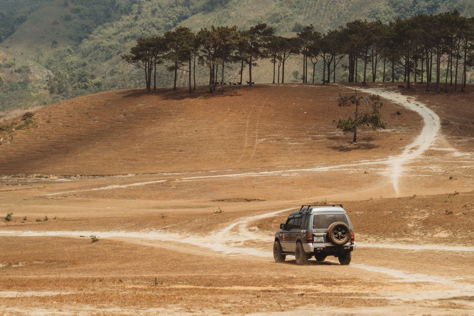 Off-road adventure with an SUV navigating a scenic dirt road in the hills.
