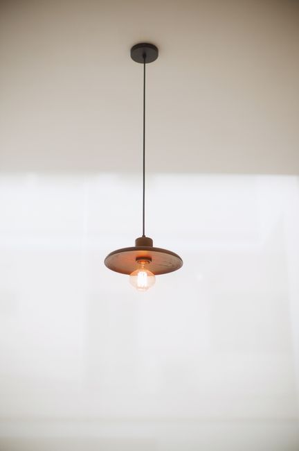 Elegant minimalist hanging lamp casting a warm glow in a modern indoor setting.