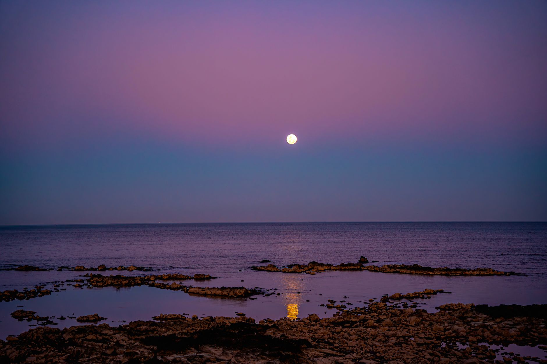 Stunning view of a moonlit coastline in Uruguay with calm waters and a serene atmosphere at dusk.