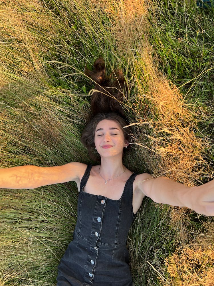 Cute Brunette Girl Laying Down In The Grass Stretching Her Hands