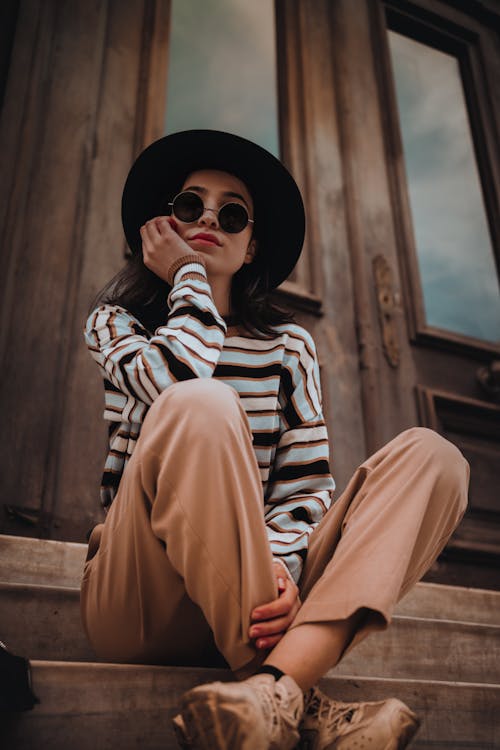 Woman in Hat and Sunglasses Sitting on Stairs