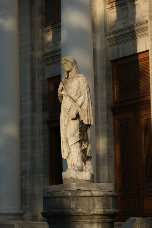 Free Elegant marble statue in front of a historic building, bathed in natural light. Stock Photo