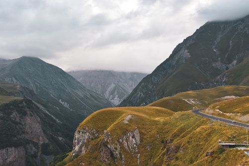 Free A winding road through lush mountains under a cloudy, foggy sky. Stock Photo
