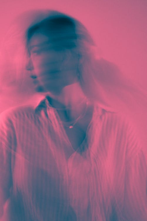 Blurry Creative Photo in Pink Light of a Woman Wearing a Shirt 