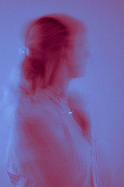 Free A blurred artistic portrait of a woman creates a dreamy, ethereal effect with red and blue tones. Stock Photo