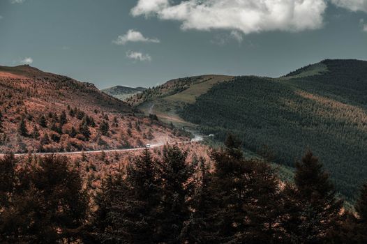 一辆汽车停靠在风景优美的公路旁，远处是山川湖泊