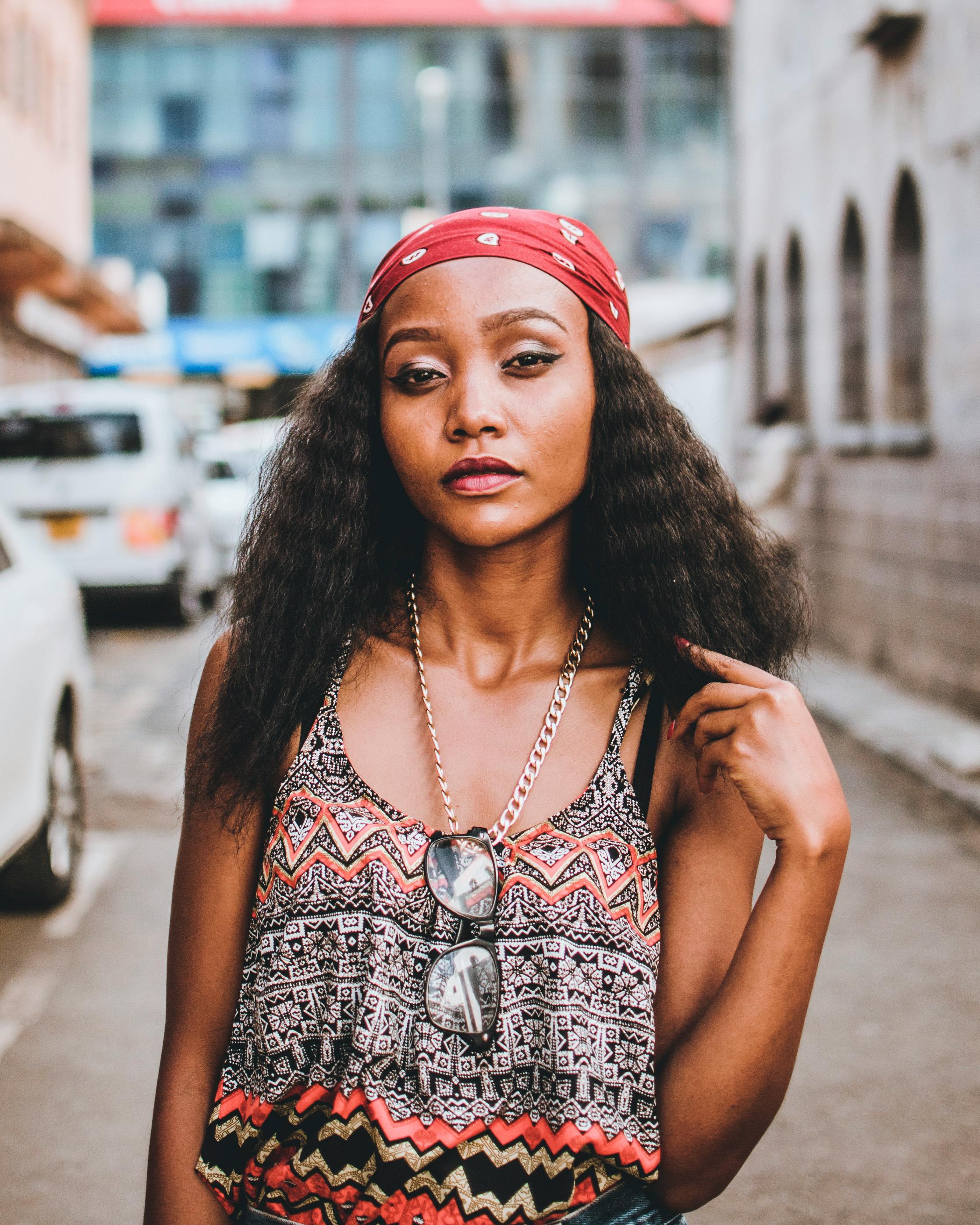 一位时尚女士戴着头巾和太阳镜，自信地在热闹的城市街道上摆出姿势