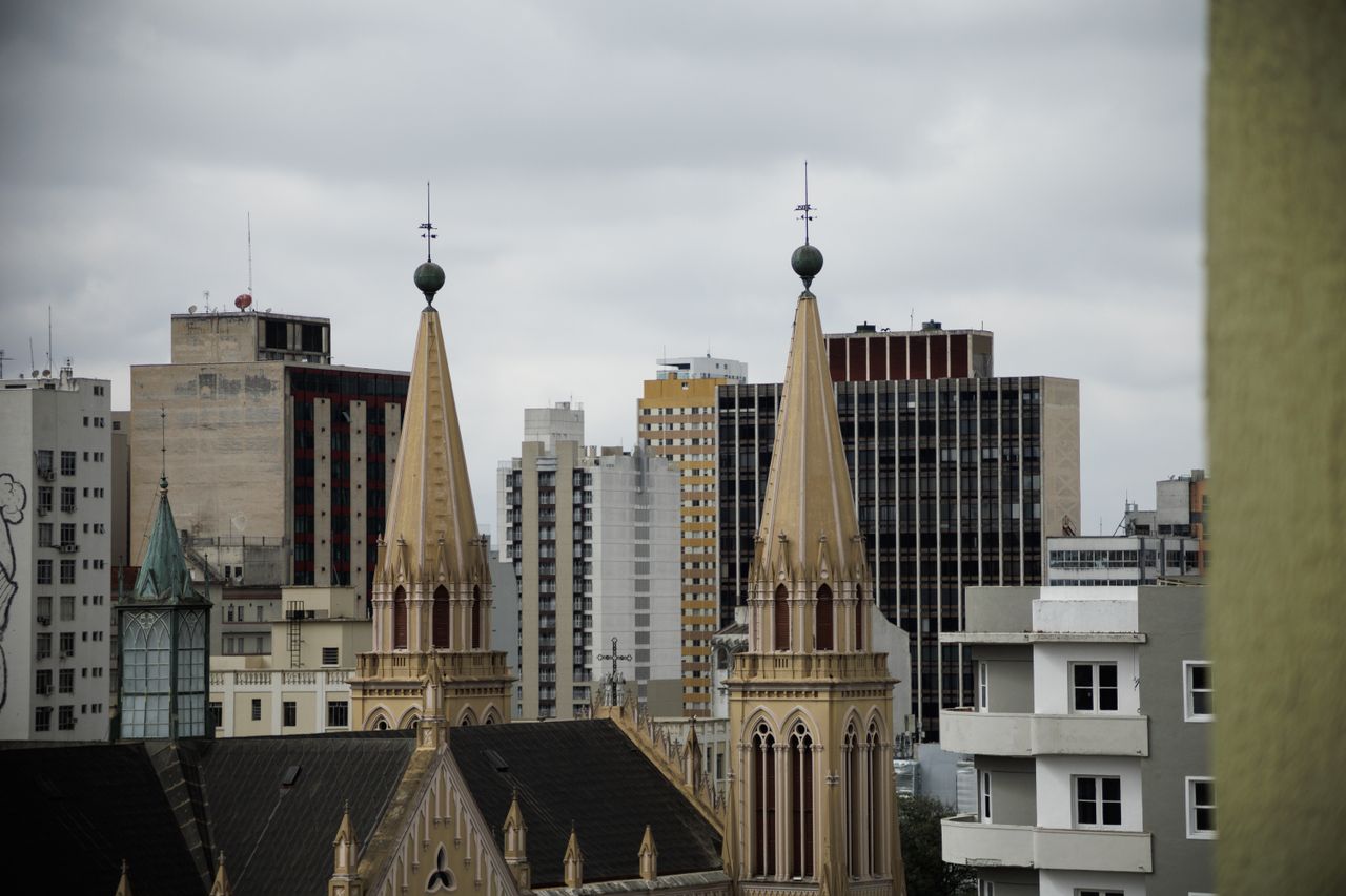 Skyline view of Curitiba with historic church spires against modern buildings.